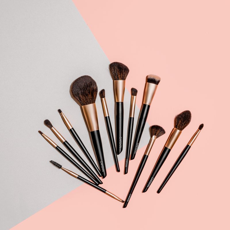 Black CAIRSKIN brushes with rose-gold ferrules on grey and peach