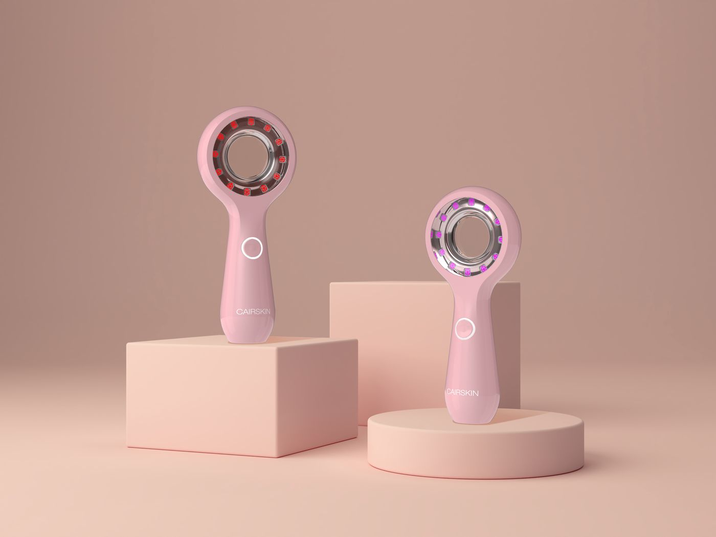 Two pink CAIRSKIN Collagen Booster handheld LED devices on pink podiums